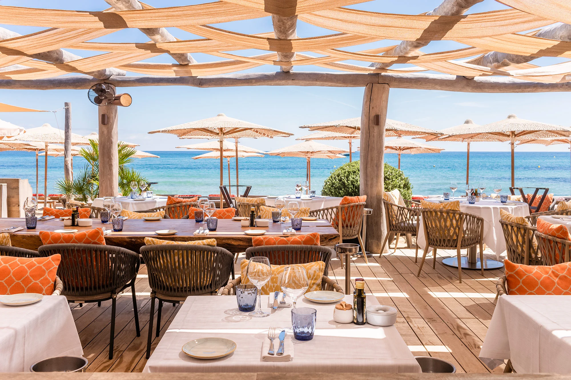 A Pampelonne beach restaurant with terracotta cushions, driftwood columns and sea view